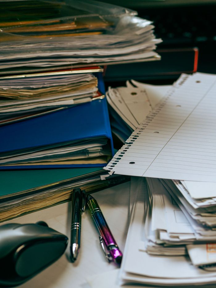 Pilha alta de pastas e documentos gastos empilhados sobre uma mesa.